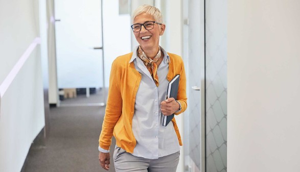 Ältere Arbeitnehmerin mit Unterlagen im Bürogebäude